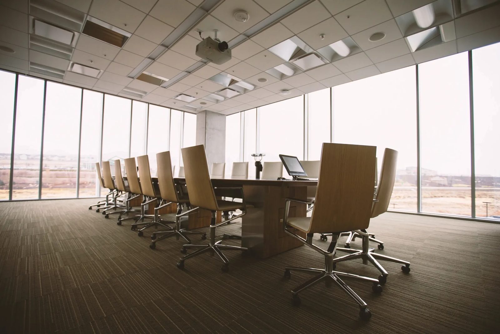 An empty boardroom with a long table and a wall of windows